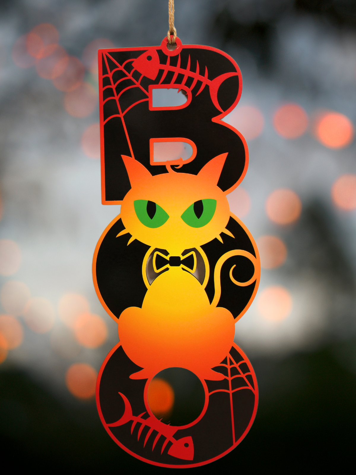 Boo Cat Halloween Sign featuring a black cat silhouette with green eyes, spider webs, and fish bones. Made from printed MDF with vibrant orange and black colors, hanging with jute twine